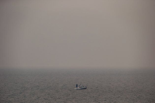 Thick smoke from wildfires fills the air as a man stands on a boat while fishing on Kamloops Lake west of Kamloops, B.C., on Tuesday August 1, 2017.