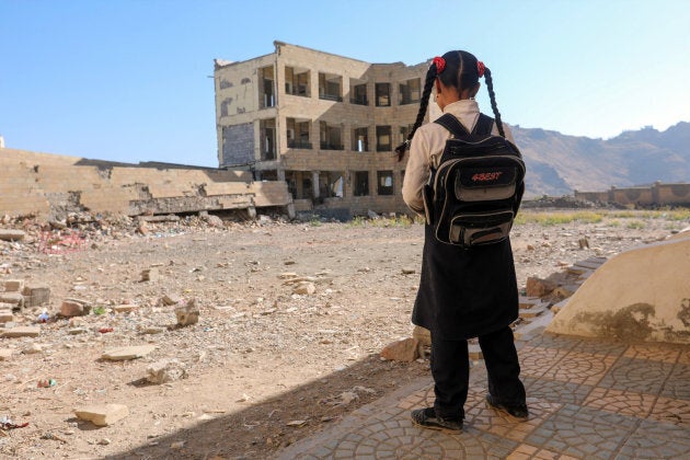 A Yemeni school girl stands outside a school on March 16, 2017, that was damage in an air strike in the southern Yemeni city of Taez.