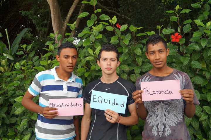 Members of a Champions of Change club in Hondorus hold cards reading masculinity, equality, tolerance.