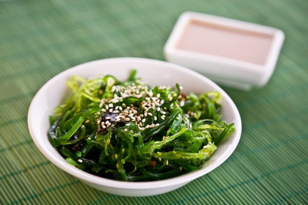 Wakame seaweed salad with nut sauce, garnished with sesame seeds and red chili pepper.