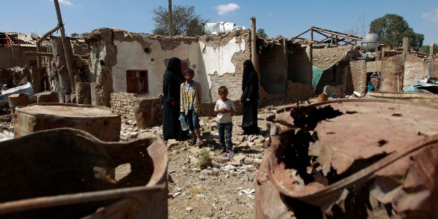 Yemeni family members stand outside their house which was damaged several months ago in an air strike by the Saudi-led coalition at a slum in the capital Sanaa, on March 12, 2016.
