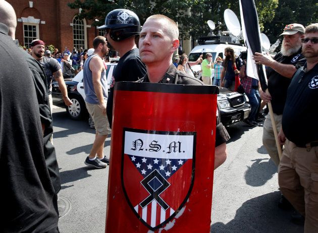 A white supremacist holds a shield with National Socialist Movement symbols on it as he arrives at a rally in Charlottesville, Va. on Saturday.