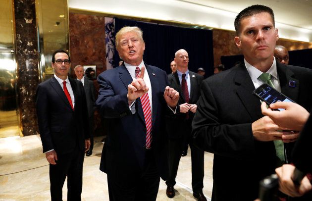 U.S. President Donald Trump stops to respond to more questions about his responses to the violence, injuries and deaths at the "Unite the Right" rally in Charlottesville as he walks away flanked by U.S. Treasury Secretary Steven Mnuchin (left) and U.S. Secret Service agents (right) after speaking to the media in the lobby of Trump Tower in New York, August 15. Trump's blaming of "both sides" for the violence has damaged his credibility.