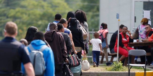 A group of asylum seekers wait to be processed after being escorted from their tent encampment to Canada Border Services in Lacolle, Que., Aug. 11, 2017.