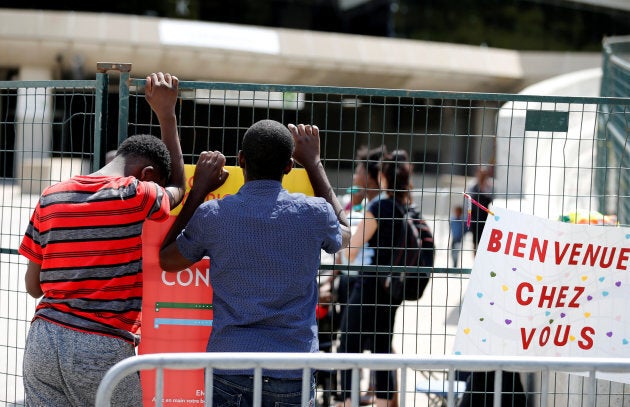 A young refugee from Angola, left, searches with a friend for his father at Olympic Stadium, one of the temporary centers housing new asylum seekers entering into Canada in Montreal, Que., Aug. 7, 2017.