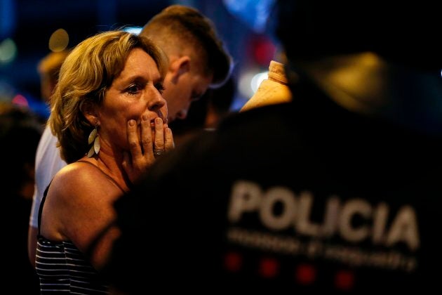 A woman is escorted by Spanish policemen outside a cordoned off area after a van ploughed into a crowd of people in Barcelona on Thursday.