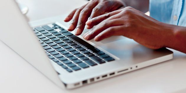 Close-up on male hands typing on laptop keyboard.