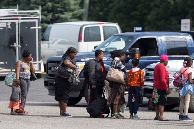 A group of asylum seekers wait to be processed after being escorted from their tent encampment to the Canada Border Services in Lacolle, Que. on Aug. 11, 2017.