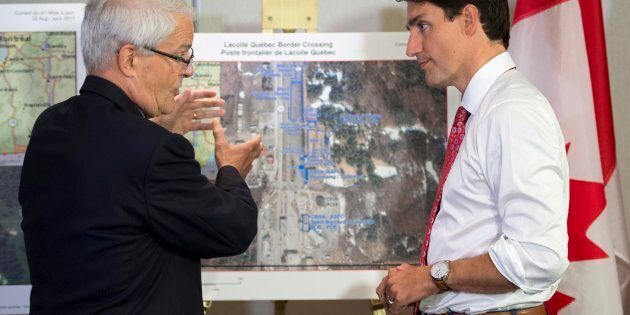Prime Minister Justin Trudeau is briefed on the refugee installations at the Lacolle border crossing by Transportation Minister Marc Garneau prior to a meeting with the Intergovernmental Task Force on Irregular Migration on Aug. 23, 2017 in Montreal.