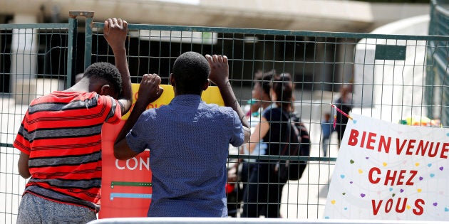 A young refugee from Angola (L) searches with a friend for his father at Olympic stadium, one of the temporary centers housing new asylum seekers entering into Canada in Montreal August 7, 2017.