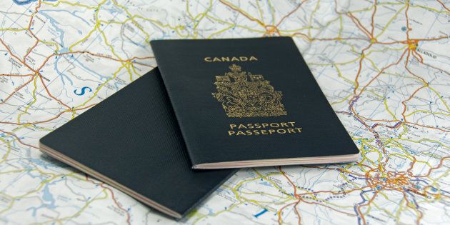 A pair of closed Canadian passports laid upon a map.