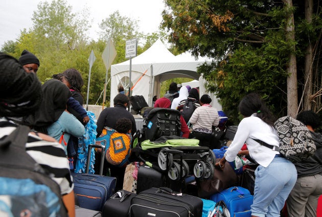 A line of asylum seekers who identified themselves as from Haiti wait to enter into Canada from Roxham Road in Champlain, New York, U.S., onAug. 7, 2017.