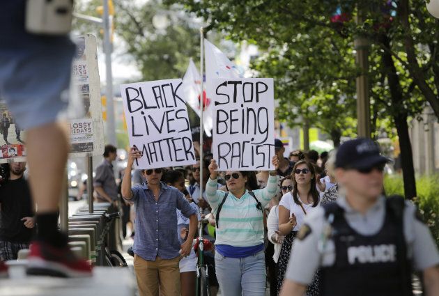 Demonstrators hold signs during an anti-racism rally in front of the U.S. Embassy in Ottawa on August 23, 2017.