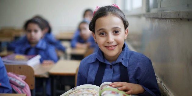 A refugee schoolchild reacts to the camera as they receive their new books on the first day of the new school year at one of the UNRWA schools at a Palestinian refugee camp al Wehdat, in Amman, Jordan, Sept. 1, 2016.