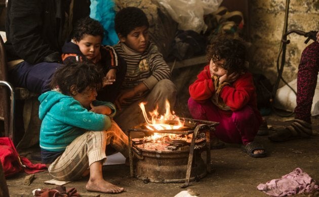 Palestinian children warm up in front of a fire in a hovel during the cold and rainy weather in the Jabalia refugee camp in the northern Gaza Strip on Jan. 28, 2017.