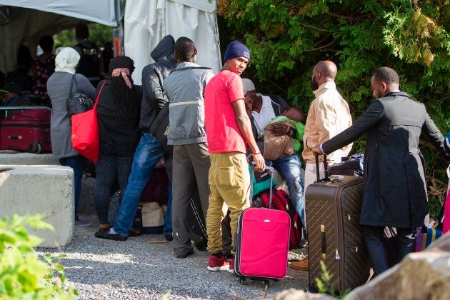 A long line of asylum seekers wait to illegally cross the Canada-U.S. border near Champlain, New York on Aug. 6, 2017.