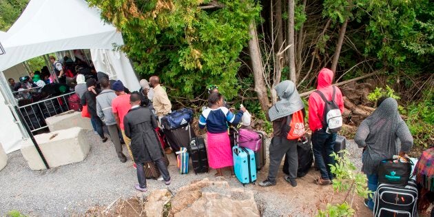 A long line of asylum seekers wait to illegally cross the Canada-U.S. border near Champlain, New York on Aug. 6, 2017.