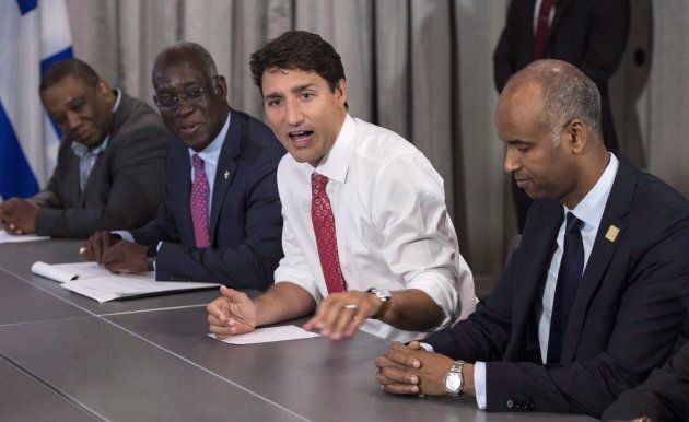Prime Minister Justin Trudeau, MP Emanuel Dubourg, left, and Ahmed Hussen, right, Federal Minister of Immigration, Refugees and Citizenship, meet with Haitian community leaders in Montreal on Aug. 23, 2017.