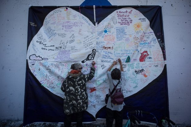 Women in Vancouver write messages on a banner commemorating those who have died B.C. as a result of the drug overdose crisis on Aug. 31, 2017.