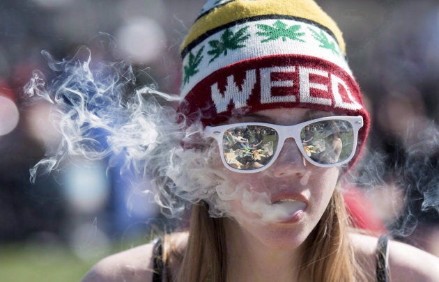 A woman exhales while smoking a joint during the annual 420 marijuana rally on Parliament hill in Ottawa on April 20, 2016.