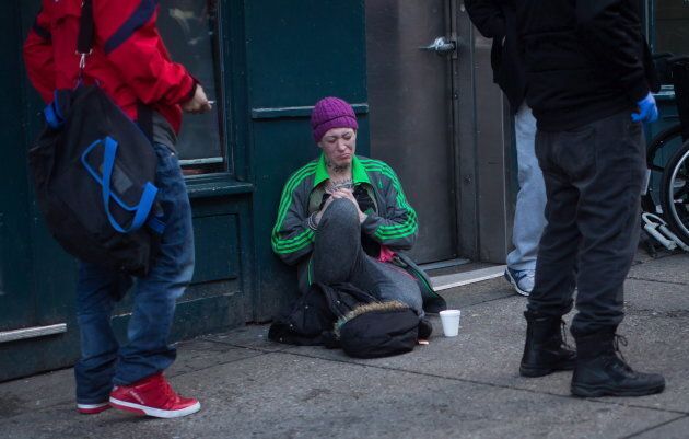 A woman sits on the ground after injecting herself with an unknown substance outside Insite, the supervised consumption site, in Vancouver's Downtown Eastside on Feb. 21, 2017.