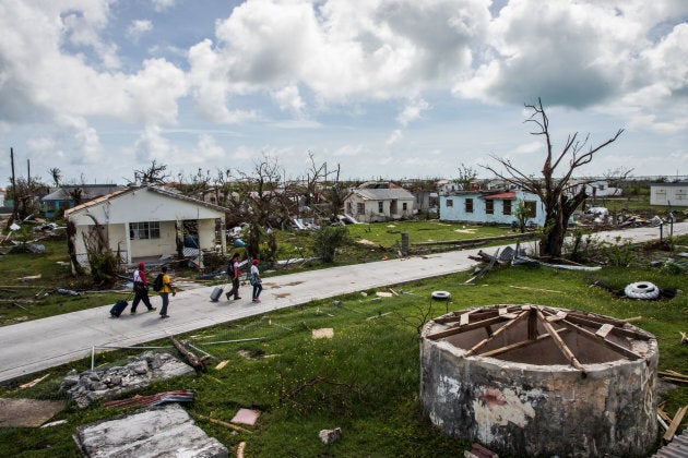 Peter Cuffy, 41, and his wife Jenita Cuffy, 40, walk behind a Red Cross crew as they look at the damages on the island of Barbuda in the aftermath of Hurricane Irma on Sunday, Sept. 24, 2017, in Codrington, Antigua and Barbuda.