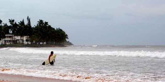 A surfer walks into the ocean in the waters of La Pared Beach in the aftermath of Hurricane Irma in Luquillo, Puerto Rico, on Sept. 7, 2017.