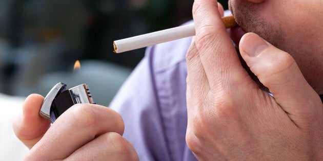 Young man lighting up a cigarette with a lighter,closeup