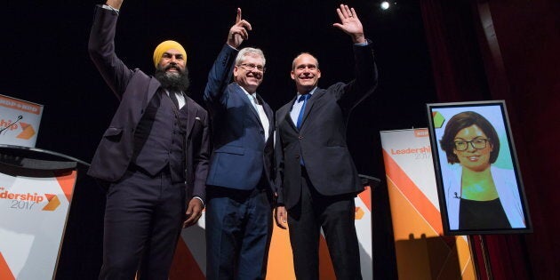 Jagmeet Singh, Charlie Angus and Guy Caron pose for a photograph as Niki Ashton is seen on a television screen via satellite from Ottawa before the NDP leadership debate in Vancouver on Sept. 1, 2017.