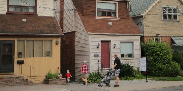 A family passes a house for sale listed at a price of $999,000 on Mount Pleasant Road in Toronto, Aug. 6, 2017.
