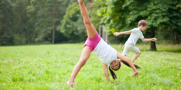 A child does a cartwheel in a field.