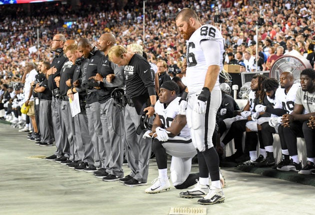 Oakland Raiders running back Jalen Richard (30) takes a knee as his coaching staff and tight end Lee Smith (86) stand while others sit on the bench during the national anthem prior to action against the Washington Redskins at FedEx Field.