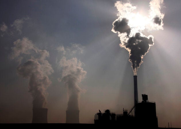 A coal-burning power plant can be seen behind a factory in the city of Baotou, in China's Inner Mongolia...