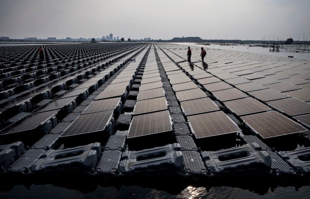 Chinese workers walk on a section of a large floating solar farm project under construction by the Sungrow Power Supply Company on a lake caused by a collapsed and flooded coal mine on June 13, 2017 in Huainan, Anhui province, China.