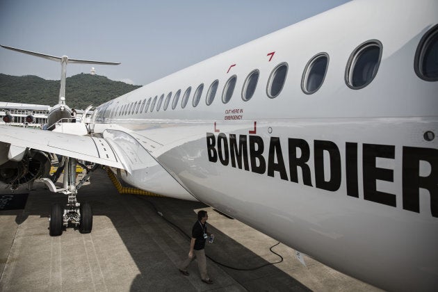 A technician walks under the belly of a Bombardier CS300 passenger jet.