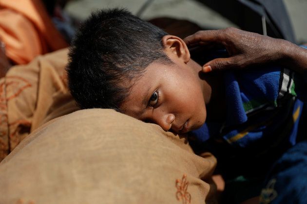 A boy is comforted as Rohingya refugees from Myanmar rest after arriving by a wooden boat to the shore of Shah Porir Dwip, in Teknaf, near Cox's Bazar in Bangladesh, Oct. 1, 2017.