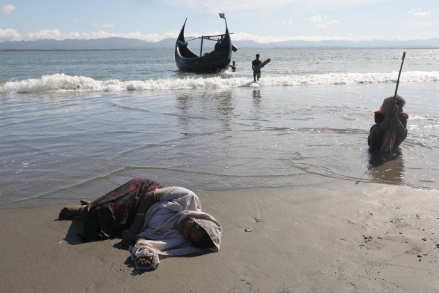 Women collapse from exhaustion as Rohingya refugees arrive by a wooden boat from Myanmar to the shore of Shah Porir Dwip, in Teknaf, near Cox's Bazar in Bangladesh, Oct. 1, 2017.