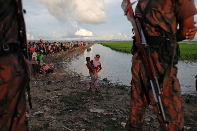 Bangladeshi border guards watch as Rohingya refugees who fled from Myanmar make their way through the rice field after crossing the border in Palang Khali, Bangladesh Oct. 9, 2017.