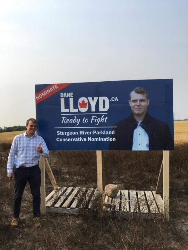 Sturgeon River-Parkland Conservative candidate stands next to a campaign sign.