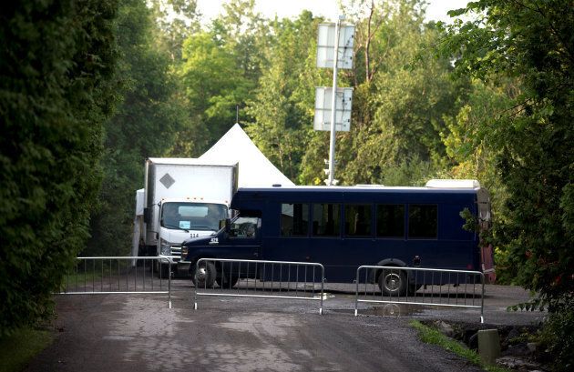 A barricade blocks the dead end road where Royal Canadian Mounted Police have set up a tent and buses for incoming refugees crossing the US-Canada border at Roxham Road in Hemmingford, Que., Aug. 3, 2017.