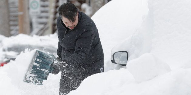 Danny Luis shovels snow around his car after a late winter storm in Montreal on March 15, 2017.
