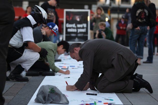 Kingston's Mayor Bryan Paterson writes messages for Gord Downie of the Tragically Hip on a banner in downtown Kingston, Ont., on Wednesday.