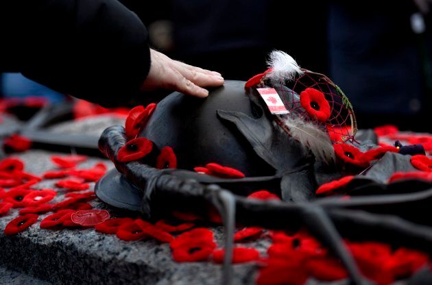 A man touches the helmet on the Tomb of the Unknown Soldier after laying a poppy following the National Remembrance Day Ceremony.
