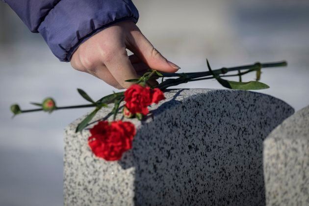 Sarah Markovich places a carnation on the grave marker of a veteran following a Remembrance Day service in Calgary.