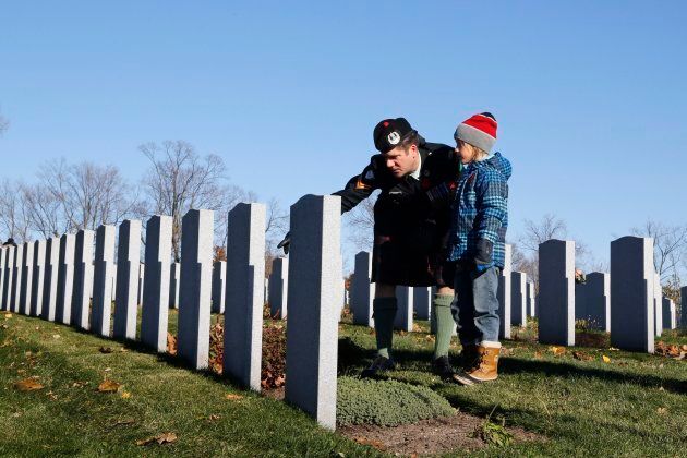 Corporal David Harding of the Cameron Highlanders and his son Silas, 8, visit the National Military Cemetery during a ceremony on Remembrance Day in Ottawa.