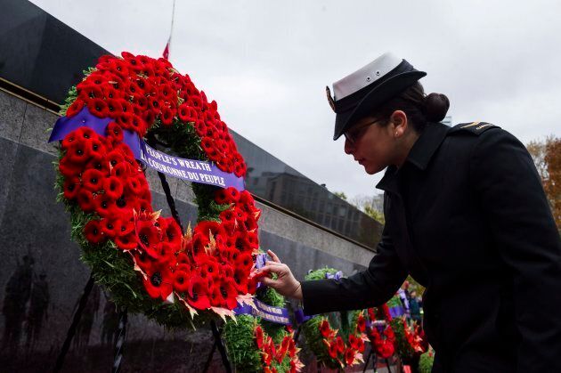 A member of the Canadian Military places a poppy on the public wreath during Remembrance Day services at Queens Park in Toronto.