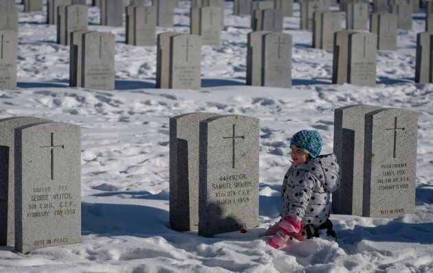 A young girl plays amongst veteran's grave markers following a Remembrance Day service in Calgary.