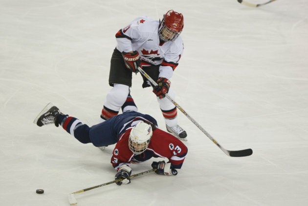 Forward Caroline Ouellette #13 of Canada knocks down forward Julie Chu #13 of the USA as she tries to play the puck during the women's ice hockey gold medal game on Feb. 21, 2002 at the Salt Lake City Winter Olympics.