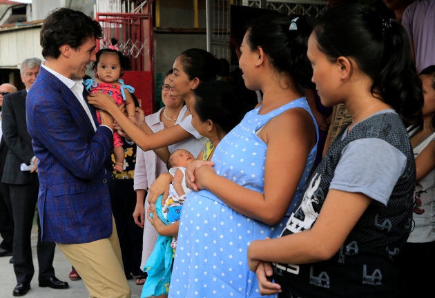 Prime Minister Justin Trudeau carries a baby during his visit at a non-governmental organization in Manila, Philippines, Nov. 12, 2017.