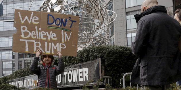 A boy stands with a sign protesting against U.S. Republican presidential candidate Donald Trump, outside the Trump International Hotel and Tower in midtown Manhattan in New York, March 19, 2016.